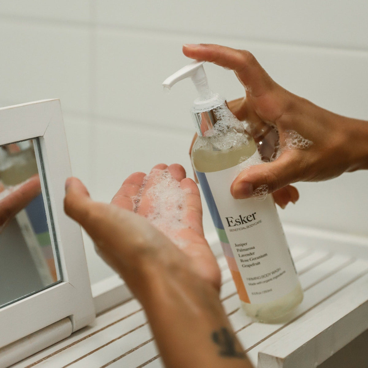 Pumping Esker Firming Body Wash onto the hand in the shower