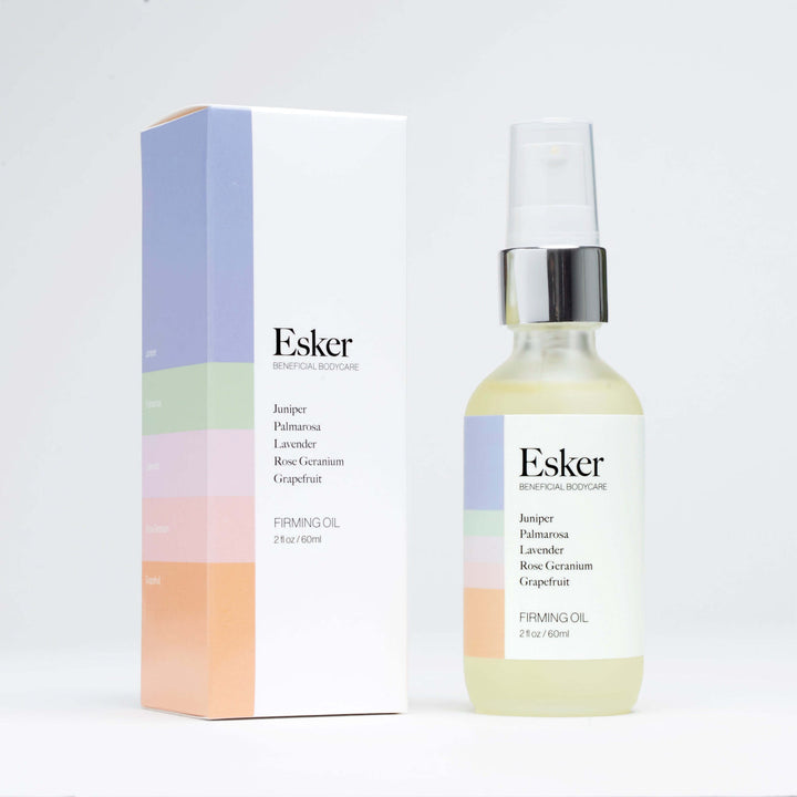 Esker Firming Body Oil bottle beside its striped box